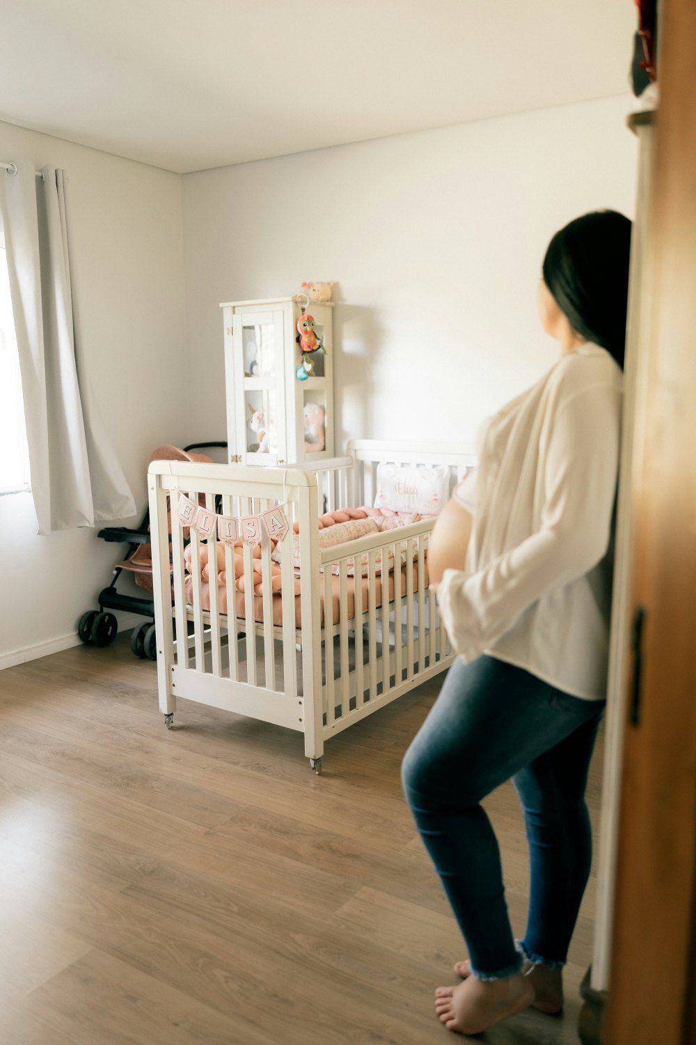 Gestante na porta do quarto do bebê, com o berço já montado